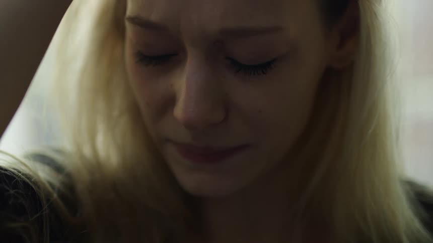 A woman brushes hair out of her face while crying