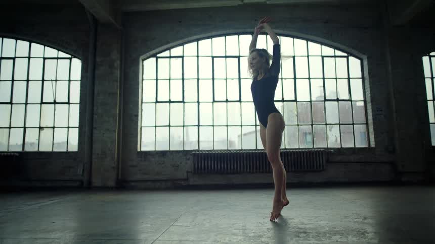 A woman leaps as she dances in a building