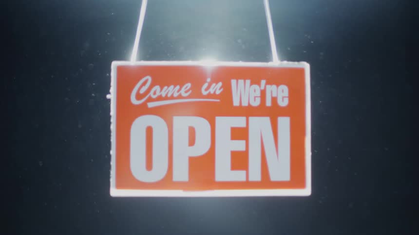 A light is behind an open sign on a window