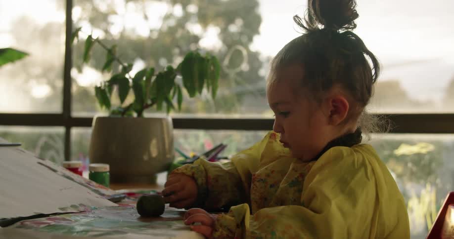 A little girl is painting on paper with a sponge brush