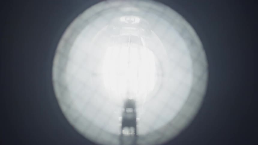 A light bulb begins to glow yellow then brightens to a glaring white light