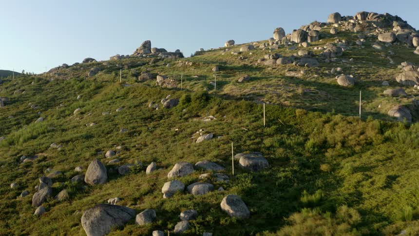 A car drives up a road on a hillside covered in grass and rocks