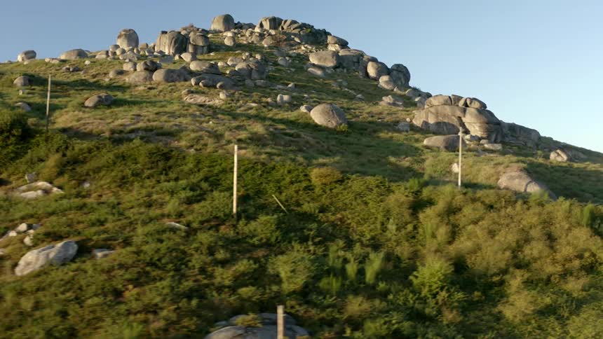 Large boulders cover the top and dot the side of a tall hill