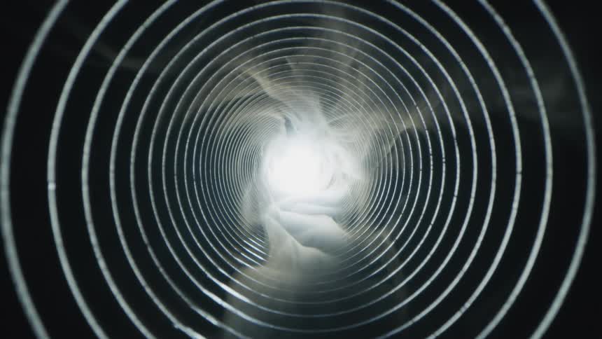 A wispy smoky image moves through a tunnel of circles toward a light