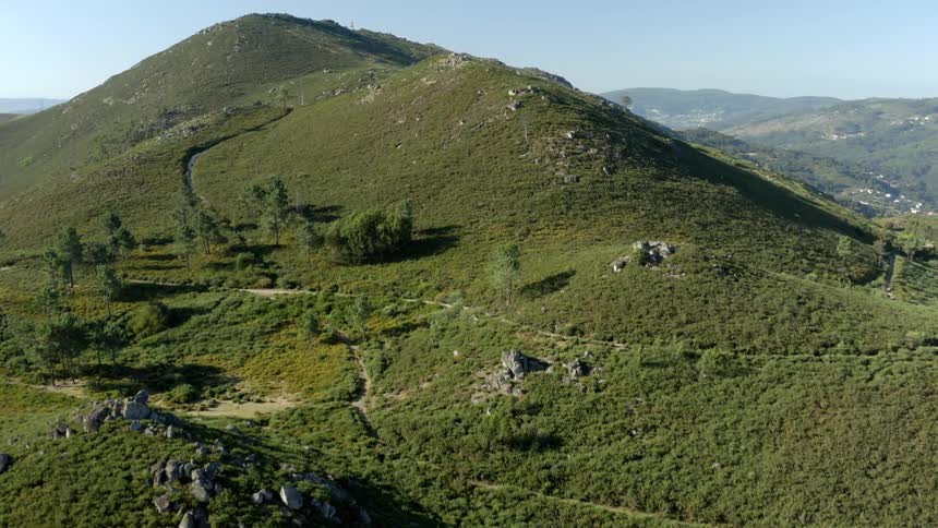 A narrow road winds along the side of a tall hill