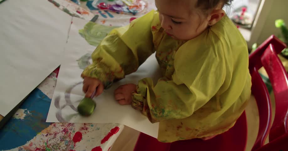 A child is painting on paper with a sponge brush