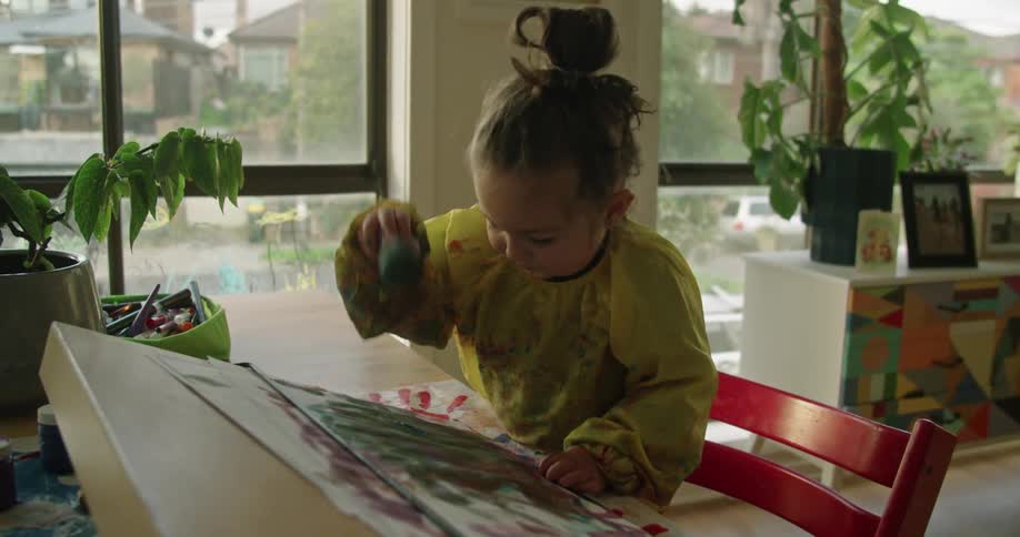 A young girl paints at home