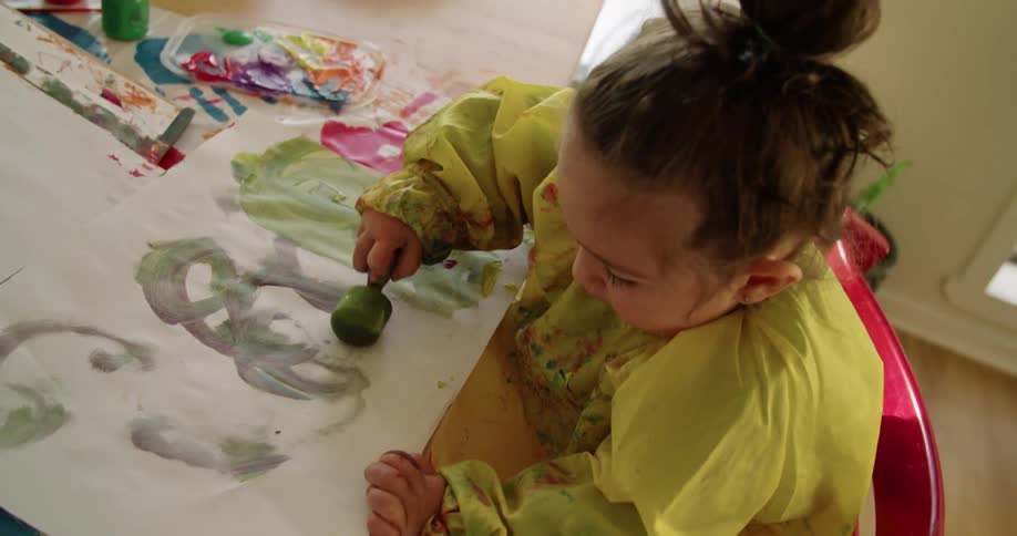 A child is painting on paper with a sponge brush