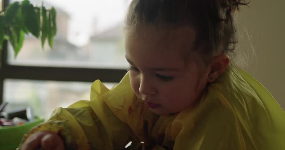 A child is painting on paper with a sponge brush