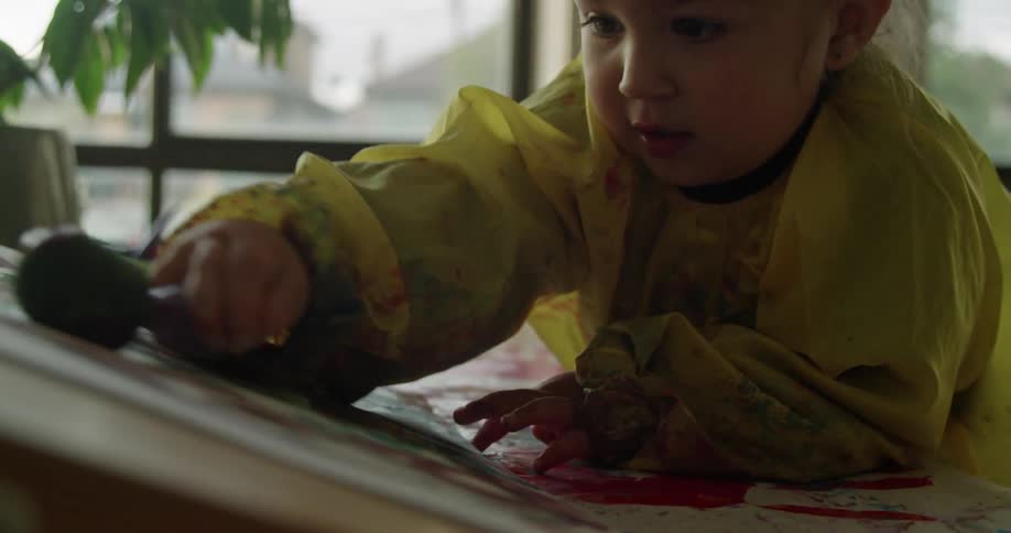 Toddler painting with a brush on paper at home