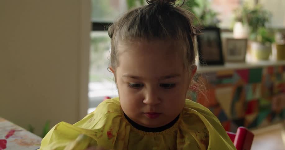A child is painting on paper with a sponge brush