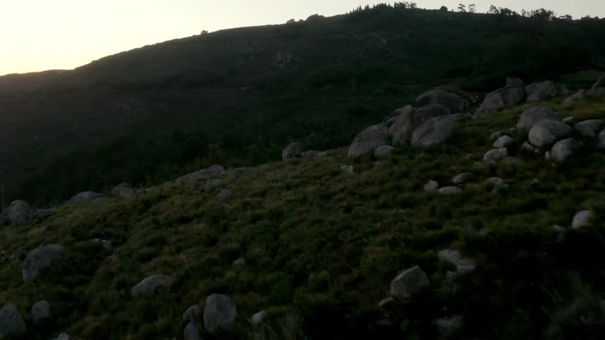 Large boulders dot the side of rolling hills