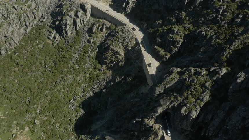 Aerial view of cars traveling on a mountain road and through a tunnel
