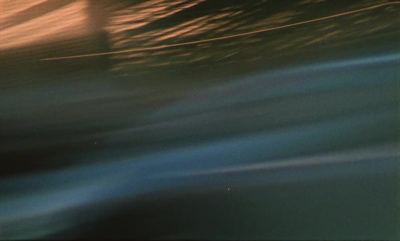 Pedestrians walk on a city sidewalk then car lights and city lights blur