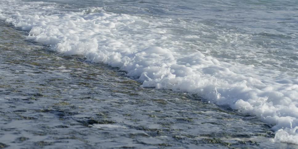 Waves crash against the sand on a beach