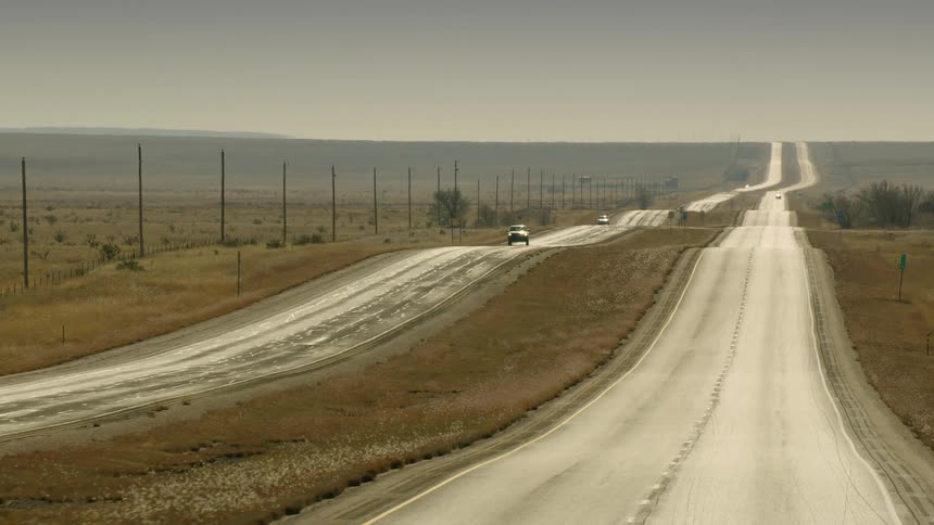 Cars travel on a long desolate stretch of road