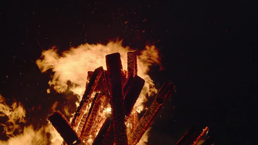 Orange flames consuming wood on a burning bonfire at night