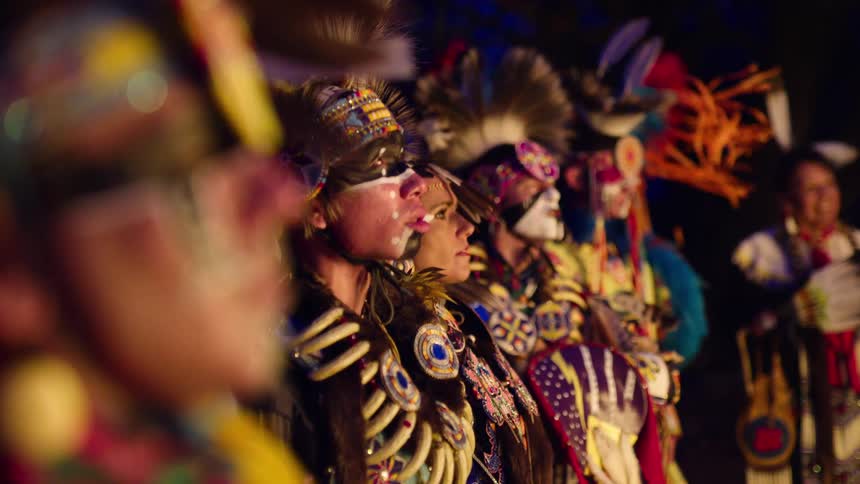 Men and women with traditional native american clothing with feathers