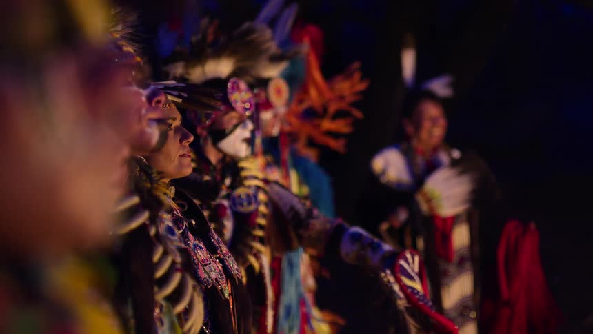 A group of native people in full regalia are participating in a ceremony