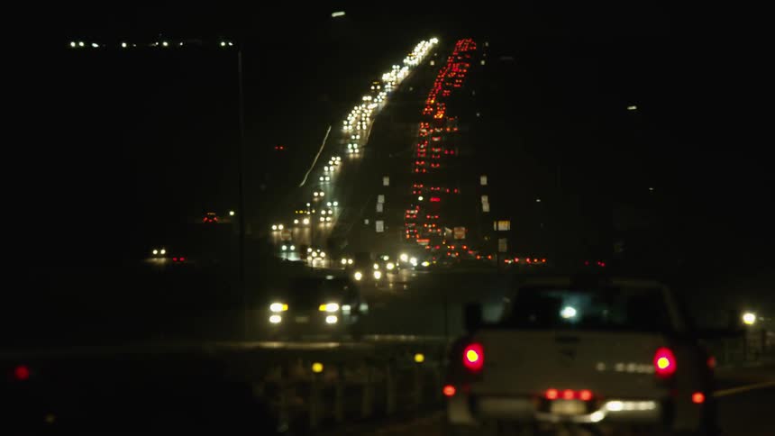 A view of dense traffic flowing in two directions on a highway at night