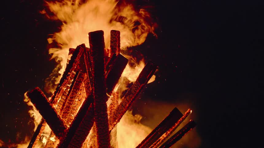 Flames grow taller as a bonfire burns outdoors