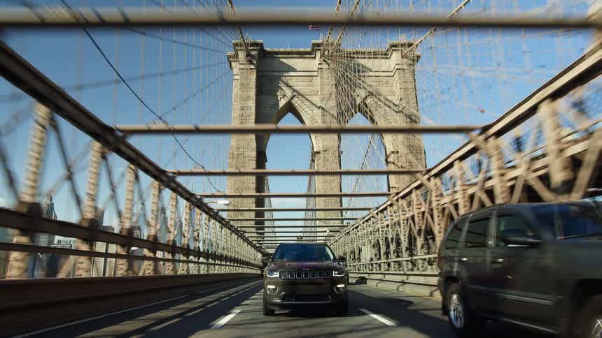 Cars driving over a large suspension bridge in a city in the daytime
