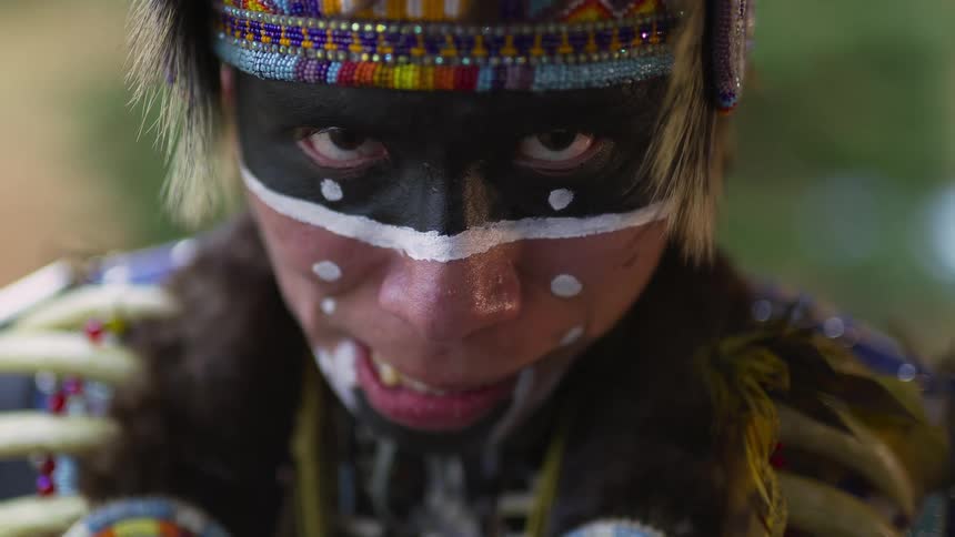 A man with traditional native american face paint with trees in the background
