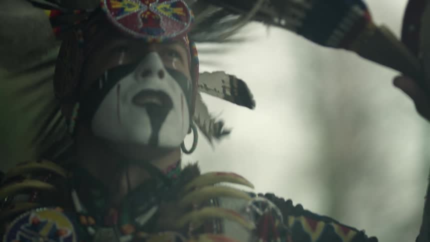 Man wearing traditional amerindian garb dances traditional dance outdoors