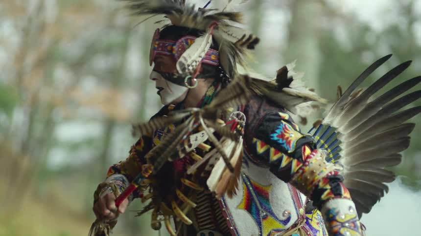 A man wearing a headdress dancing outdoors