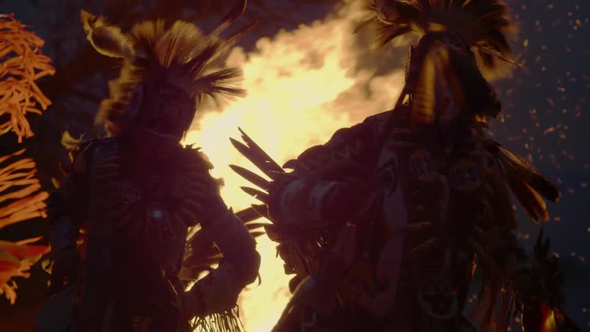 Indigenous dancers move around a large fire