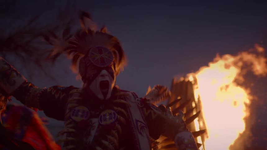 Native men in decorative headdress dance around a fire