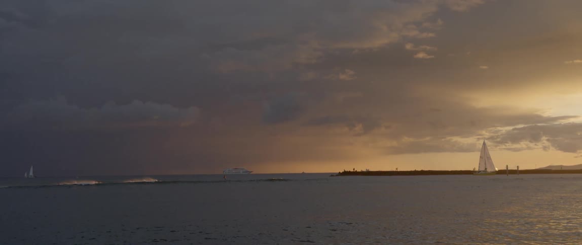A boat is sailing in the distance at sunset