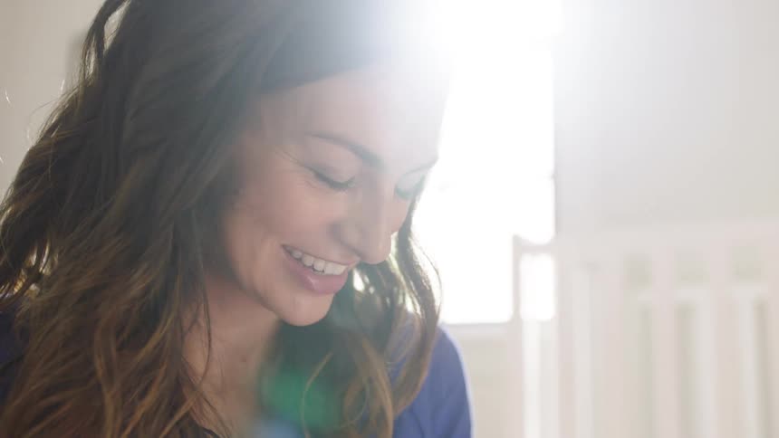 A woman with long dark hair has a big smile on her face as she is talking
