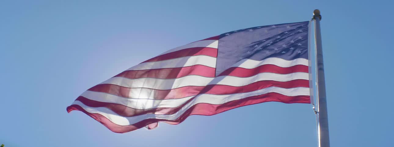 An american flag billowing in the wind on a sunny clear day
