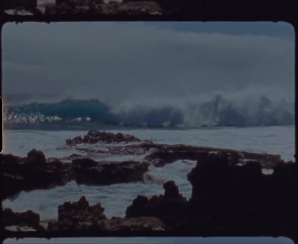 A large wave crashes on the rocky shore