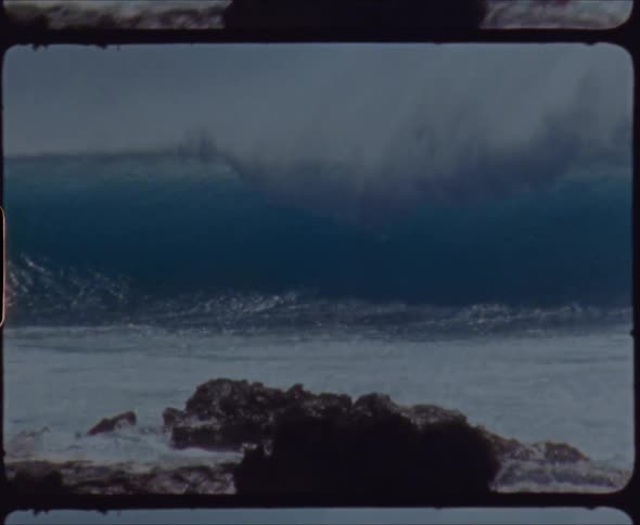 Rough waves are splashing as they roll in crashing against rocks along the coast