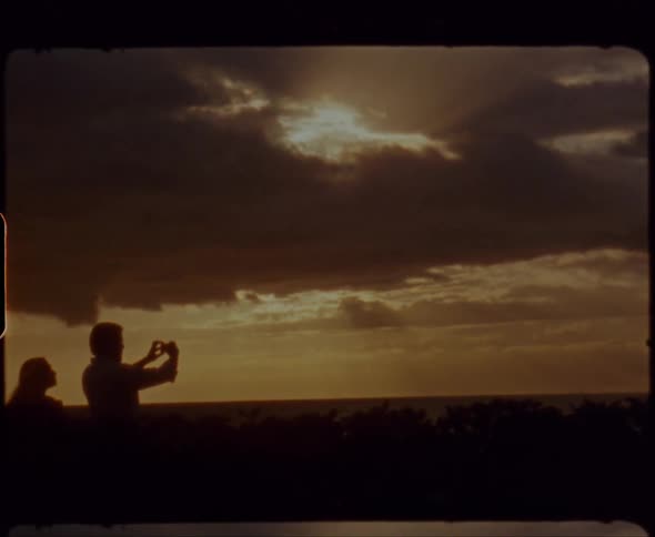 A man holds up a camera photographing the golden sky