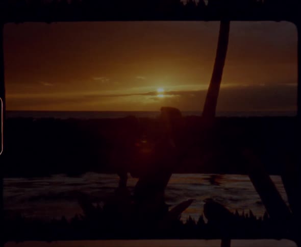 Silhouette of aman on a beach tossing a baby in air with a sunset in the background