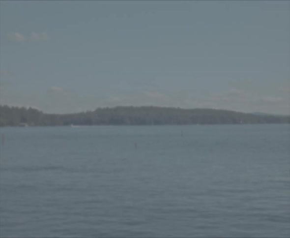 View of still sea with distant mountains seen from the coast