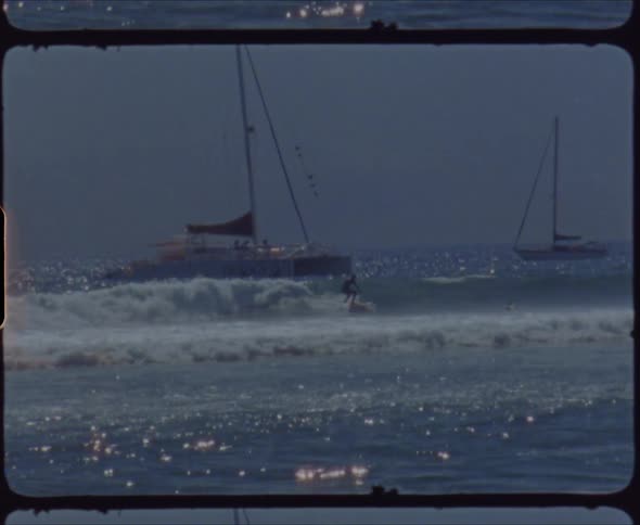A person surfing on a wave with boats the sky and clouds in the background