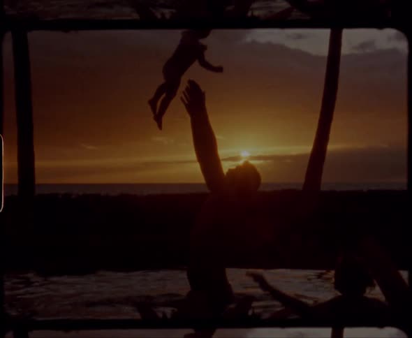A silhouette of a man throwing up and catching a baby next to a woman with the sky and clouds in the background