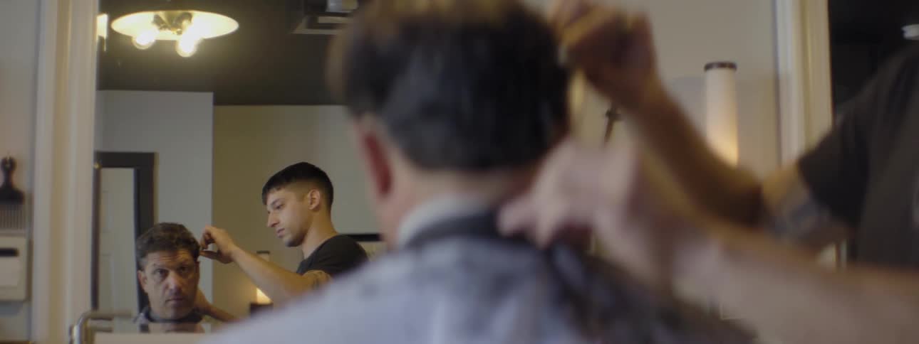 A young man cuts another man's hair