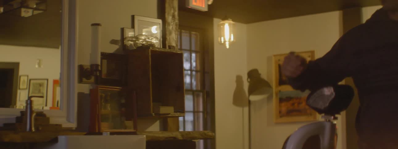 A man takes off his jacket and then turns on the lights