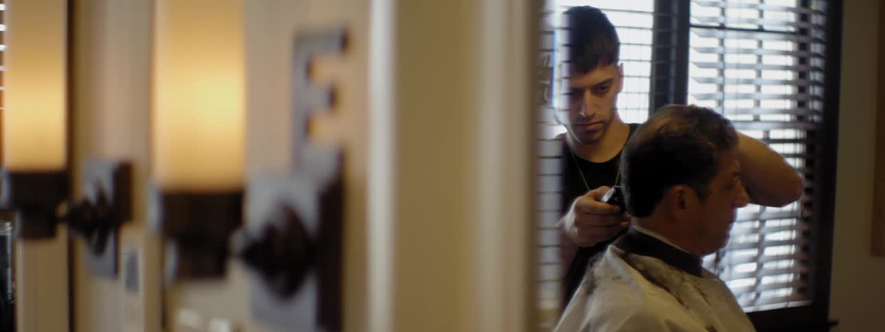 A man is cutting a person's hair in a barber shop