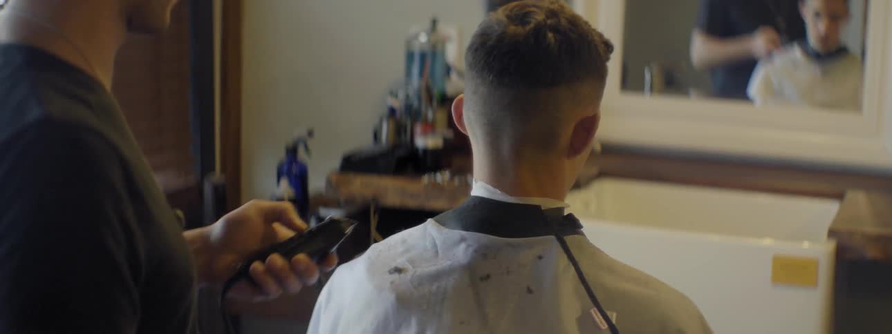 A barber uses a razor on a man in his shop