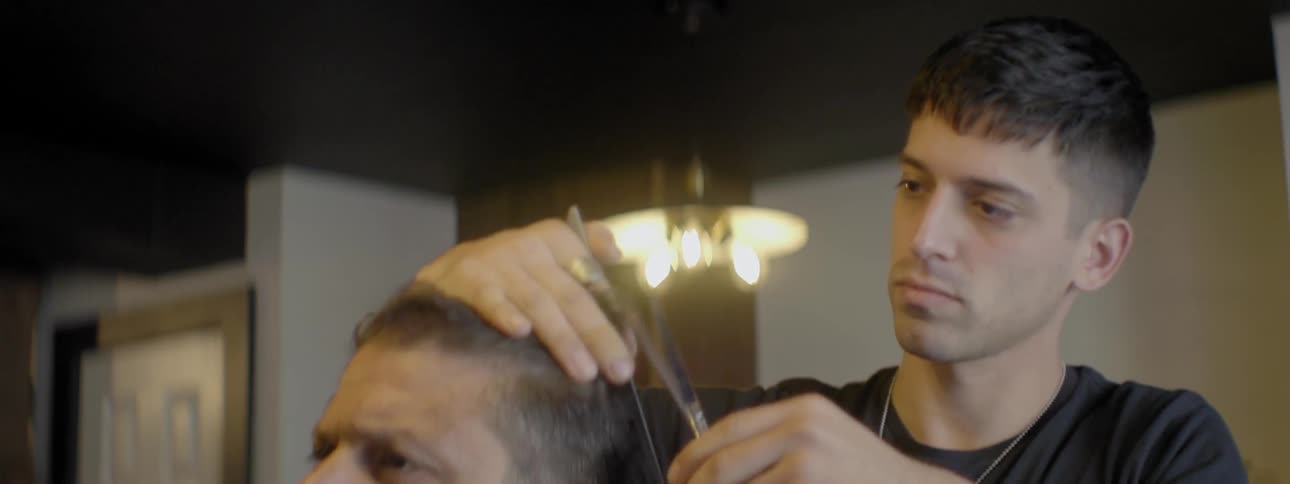 Barber trimming patron's hair with comb and scissors