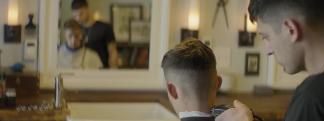 A man is getting his hair shaved in a barber shop