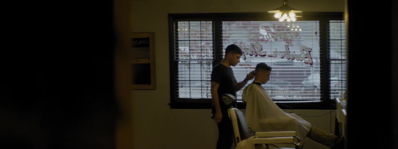A barber is shaving someone's hair in a barber shop
