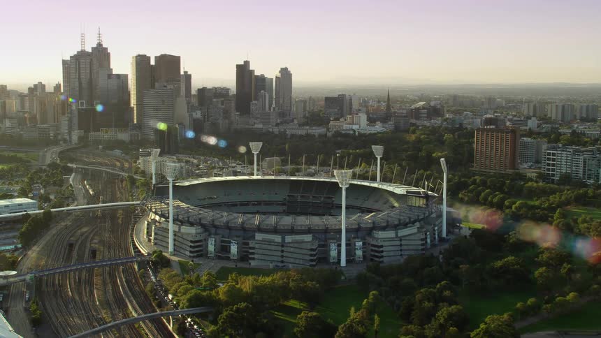 Aerial view of a stadium near the city skyline at sunset
