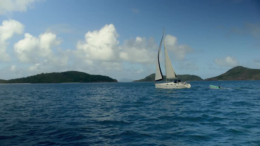 A boat and a sailboat on a body of water with land the sky and clouds in the background